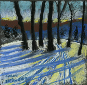Trees cast long shadows on snow, ski tracks and footprints in snow, deep blue hill and russet foliage beyond, Winter sky has yellow glow and viridian green. 12” x 12” Soft pastel on paper by Carol Skinger